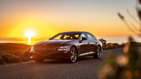 A 2022 Genesis G80 luxury sedan parked on the side of the road as the sun sets behind it