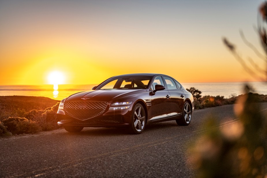 A 2022 Genesis G80 luxury sedan parked on the side of the road as the sun sets behind it