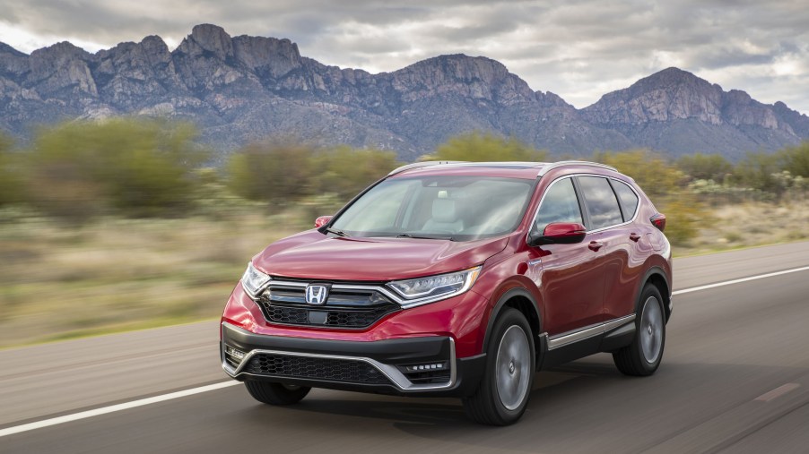 A red 2021 Honda CR-V Hybrid driving in the mountains