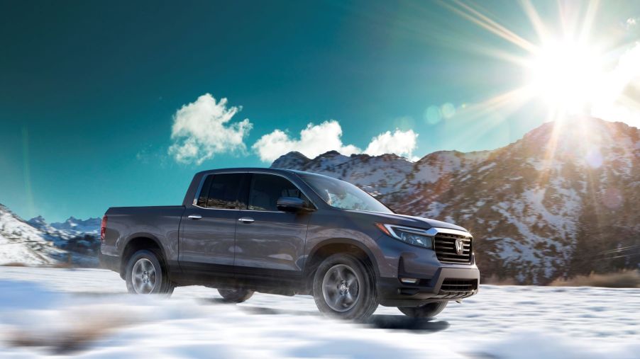 The 2022 Honda Ridgeline RTL-E compact pickup truck driving over a snowy field as the sun rises over a mountain
