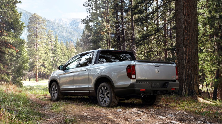A silver 2022 Honda Ridgeline midsize pickup truck parked in the woods