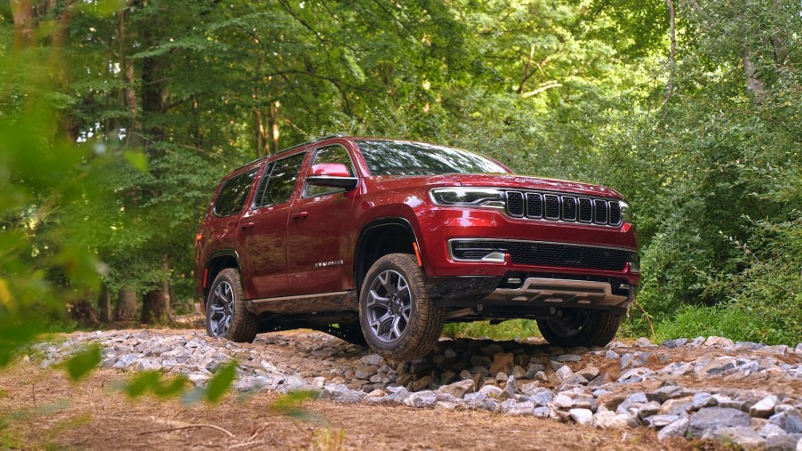 A red 2022 Jeep Wagoneer full-size luxury SUV off-roading in the woods