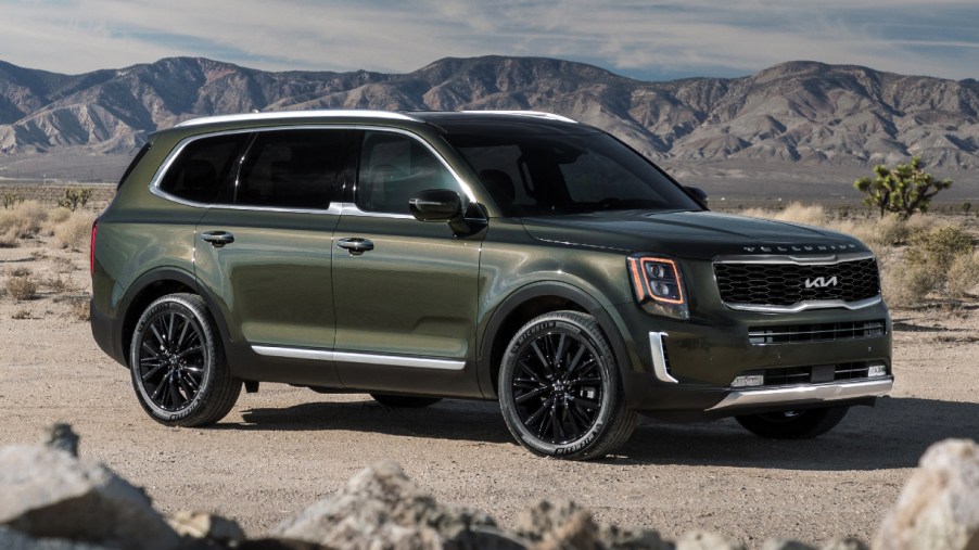 A green 2022 Kia Telluride midsize SUV is parked off-road.
