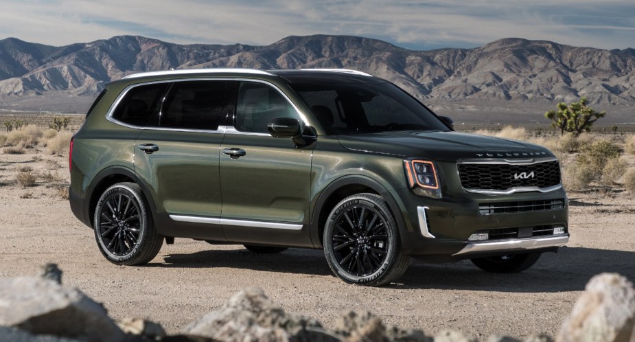 A green 2022 Kia Telluride midsize SUV is parked off-road.