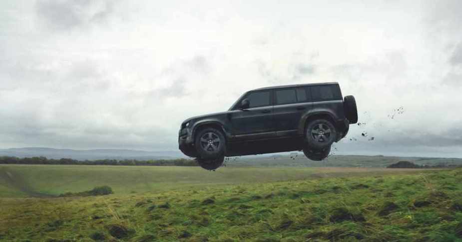 A 2022 Land Rover Defender jumping through a hillside. 