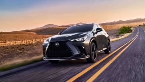 A dark gray 2022 Lexus NX 350 F Sport luxury compact SUV speeding down a barren country highway