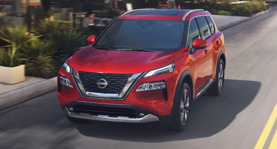 A red 2022 Nissan Rogue is driving on the road. 