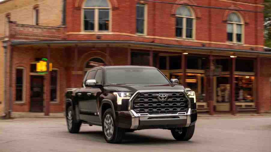 A dark color 2022 full-size pickup truck Toyota Tundra parked in front of some buildings.