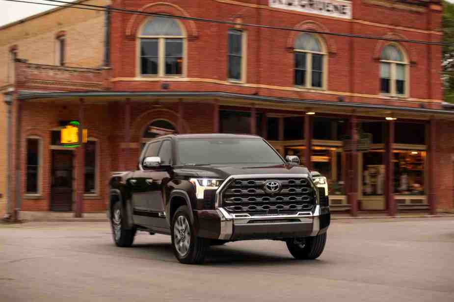 A dark colored 2022 Toyota Tundra full size pickup parked in front of some buildings.