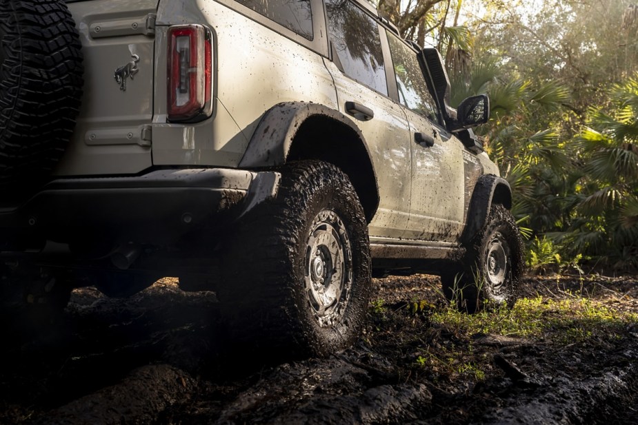 The rear view of a 2022 Ford Bronco Everglades as it plays in the mud.