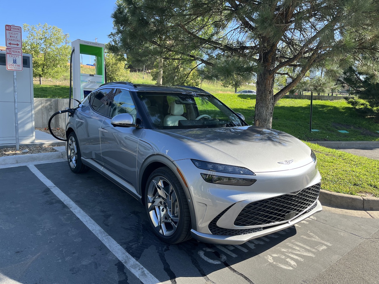 The 2023 Genesis GV60 plugged into an Electrify America charger.