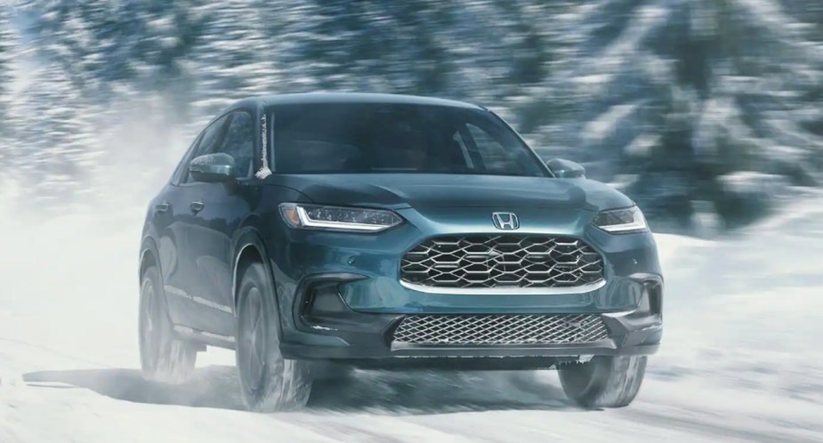 A green 2023 Honda HR-V subcompact SUV is driving in the snow. 