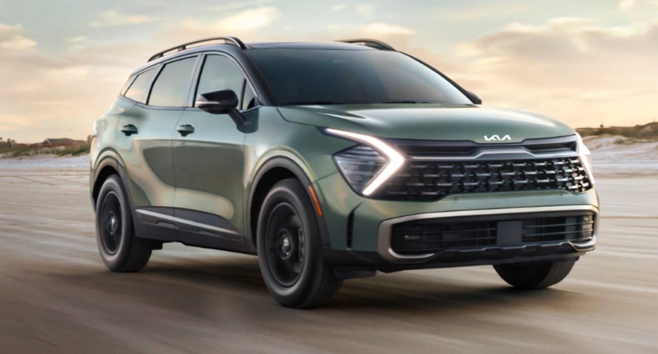 A green 2023 Kia Sportage is driving on the road. 
