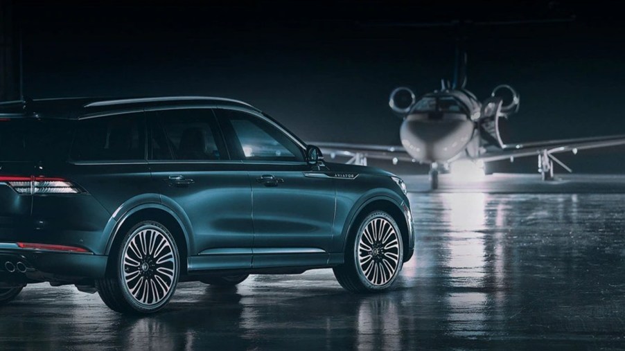Green 2023 Lincoln Aviator Black Label Grand Touring on a runway near a private jet