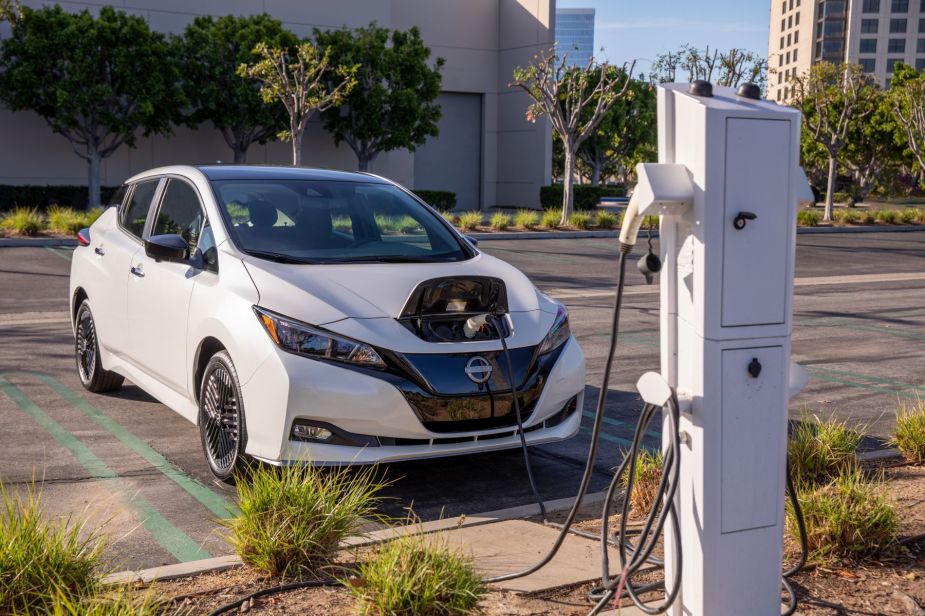 A white 2023 Nissan Leaf S electric hatchback plugged-in at a charging station