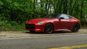 The side 3/4 view of a red 2023 Nissan Z Performance on a forest road