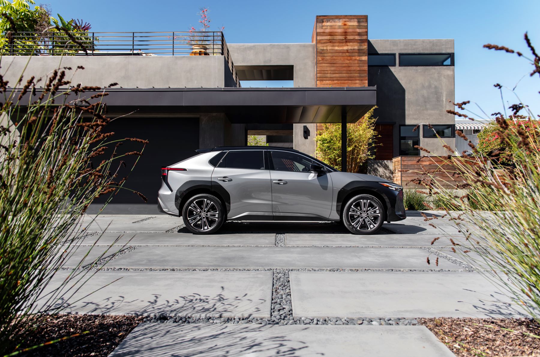 A 2023 Toyota bZ4X Limited all-electric SUV (EV) in Heavy Metal side profile shot on a concrete and rock plaza