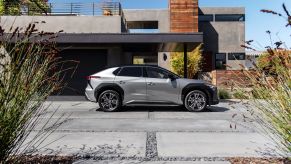 A 2023 Toyota bZ4X Limited all-electric SUV (EV) in Heavy Metal side profile shot on a concrete and rock plaza