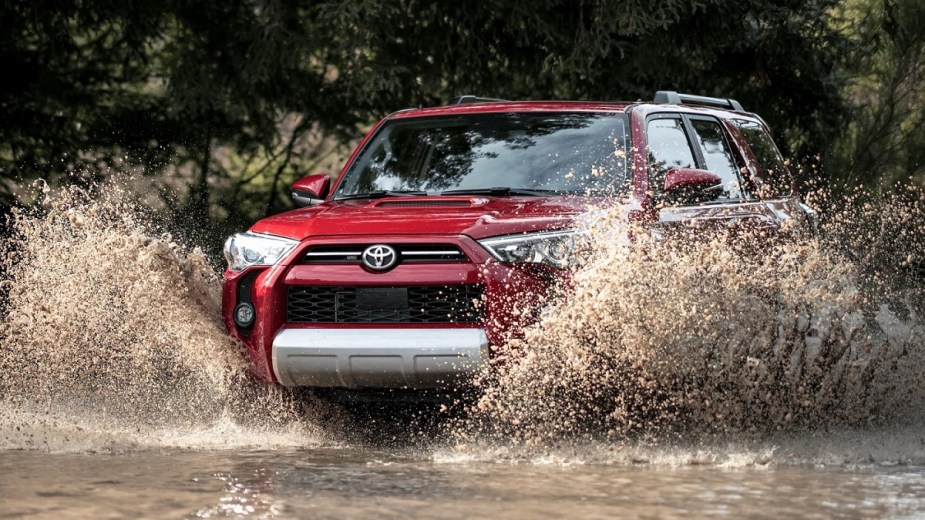 A red 2022 Toyota 4Runner splashing through mud.