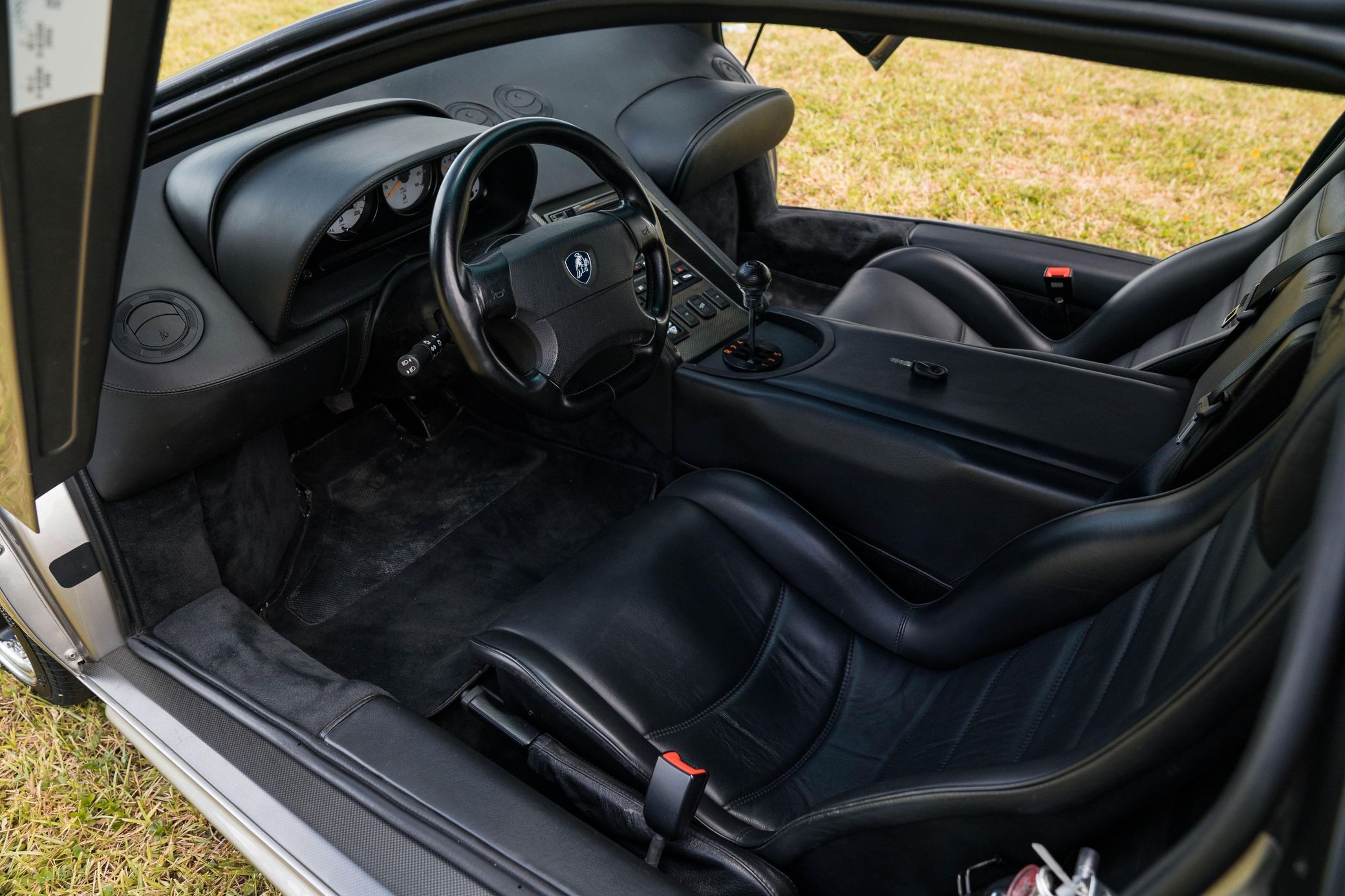 The black-leather seats and dashboard of a silver 1998 Lamborghini Diablo SV parked on a lawn with its doors open