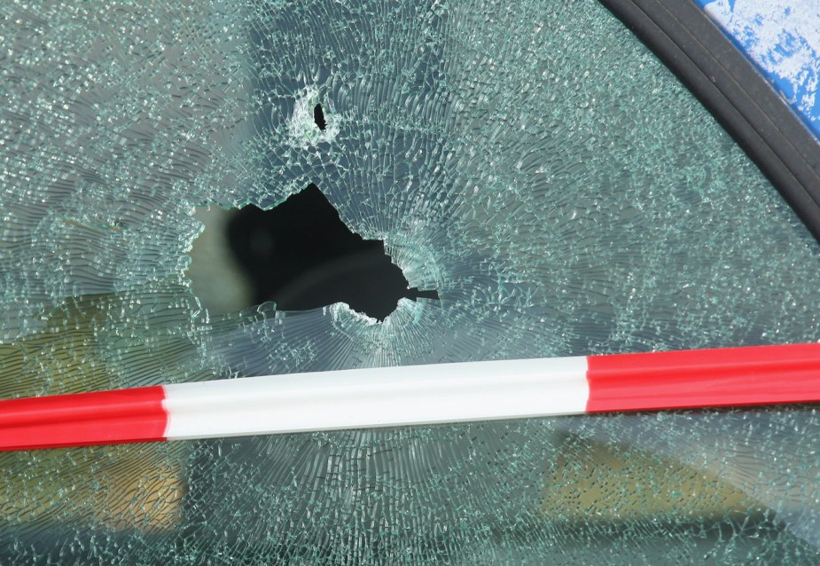 The shattered window of a car struck by a bullet is visible outside a branch of Postbank bank.