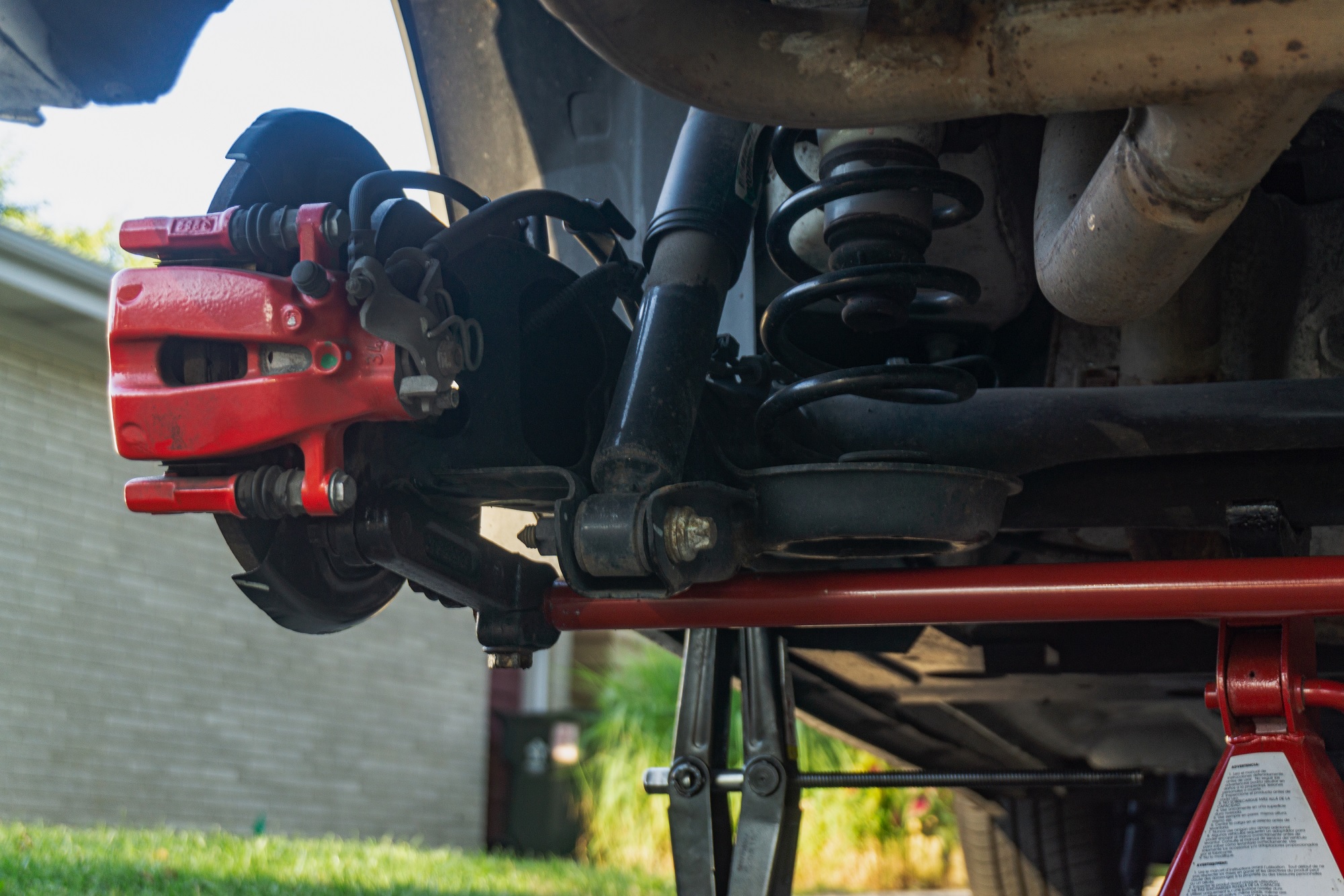 The driver's side bracket holding a red Neu-f rear torsion bar on a 2013 Fiat 500 Abarth