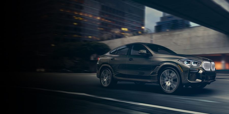 A beige 2022 BMW X6 driving through the city.