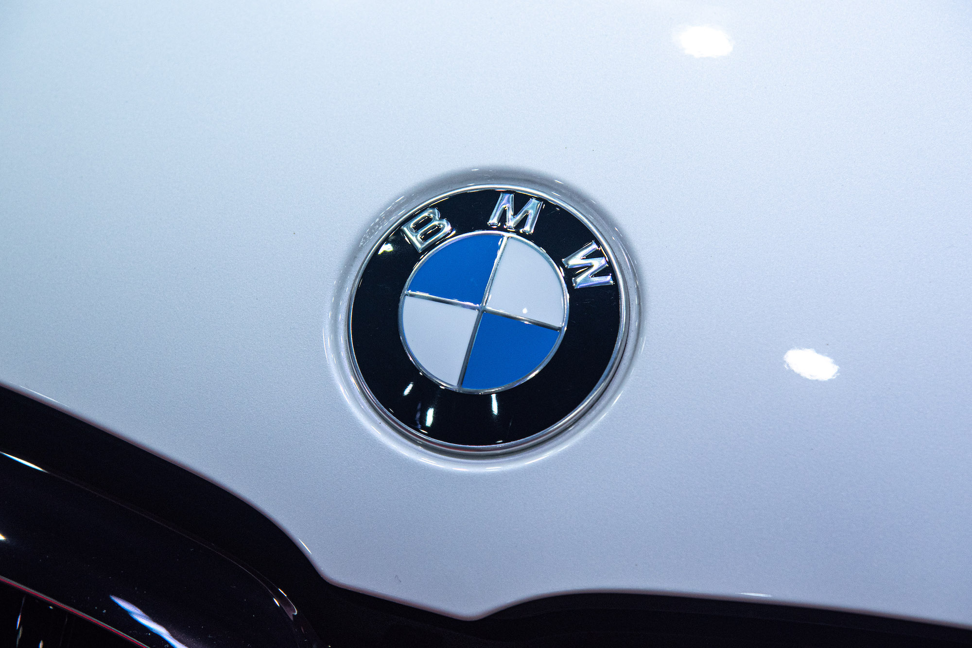 A white car with a BMW logo, with many BMW nicknames, on it.