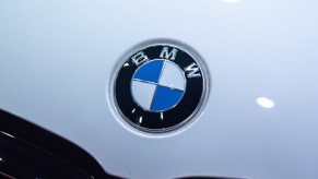 A white car with a BMW logo, with many BMW nicknames, on it.