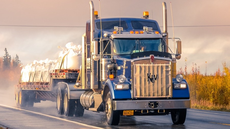Blue semi-truck driving on a highway, highlighting why truck air horns are so load