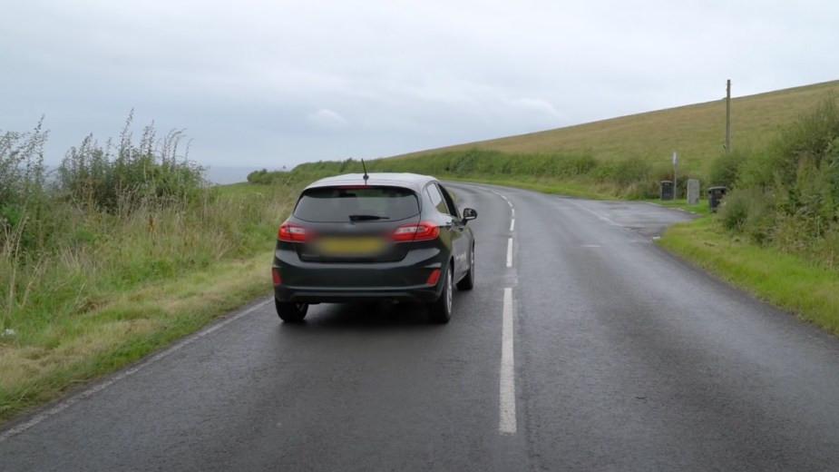 Car rolling uphill in neutral on optical illusion Electric Brae gravity hill in South Ayrshire, Scotland