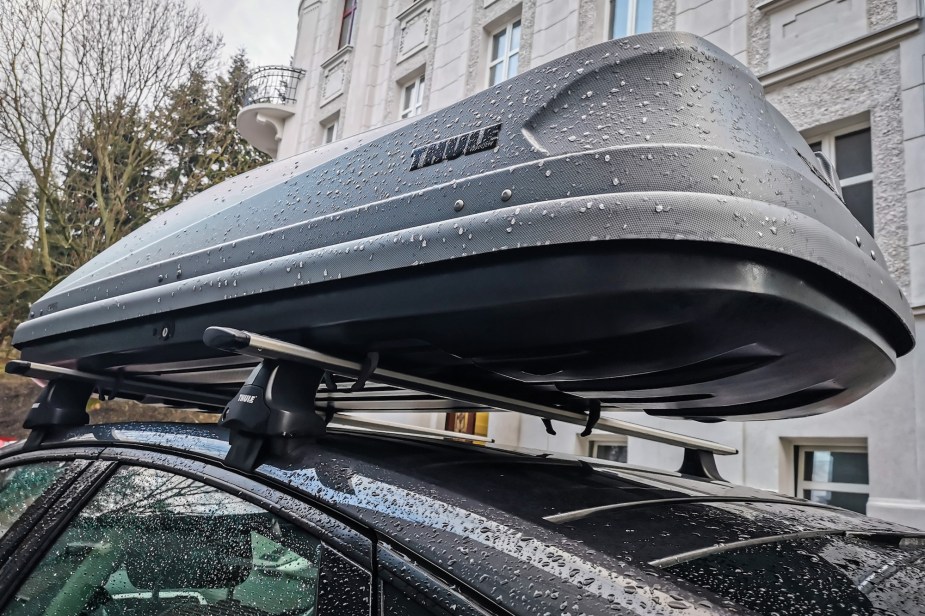 A grey cargo roof box on top of a car with roof racks. 