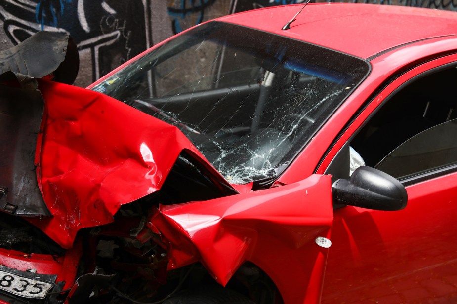 A red car accident photo with front damage. 