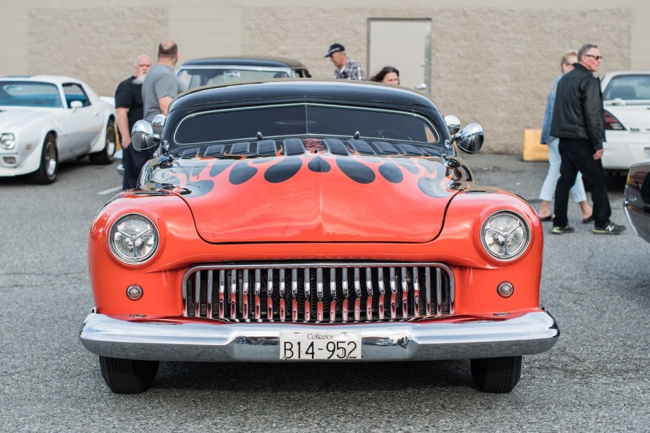 A lowered and debadghed leadsled with orange frames, parked at a car show.