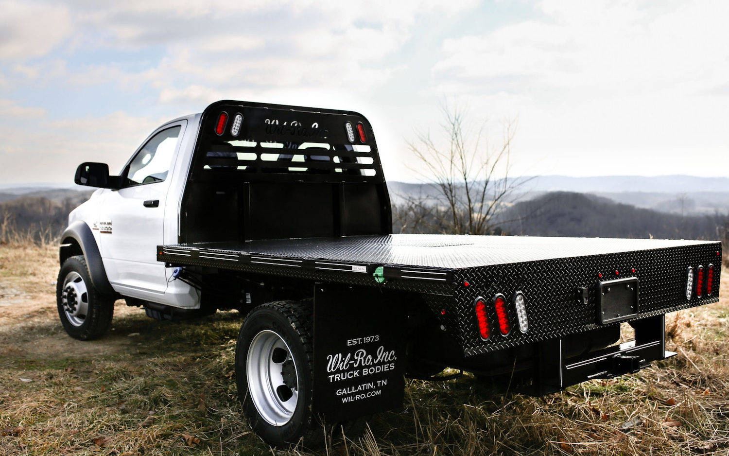This is a heavy-duty Ram pickup truck with a Cummins engine modified by Wil-Ro inc. Truck Bodies with a custom stakeside flat bed.