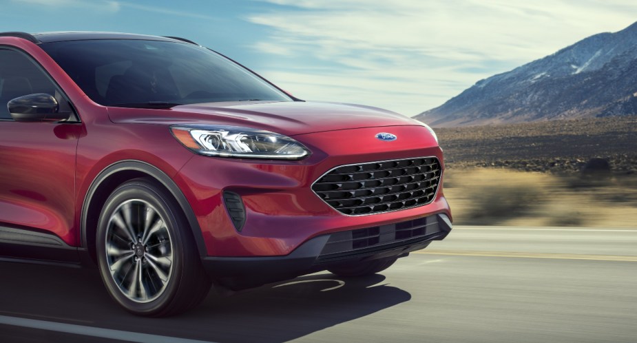 A red 2022 Ford Escape PHEV small plug-in hybrid SUV is driving on the road.