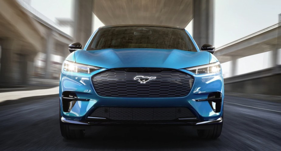 A blue Ford Mustang Mach-E electric SUV is driving.