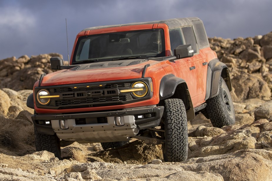 A 2022 Ford Bronco Raptor in red navigates off-road terrain.