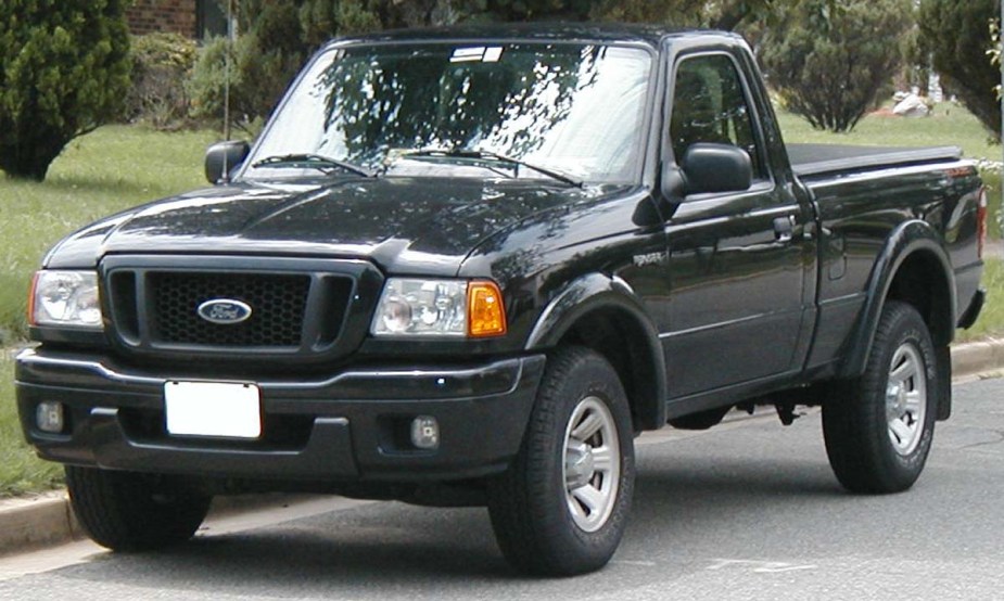 A third generation Ford Ranger with black paint sits parked in the street. 