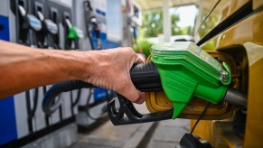 A green nozzle from a gas pump in a yellow car.