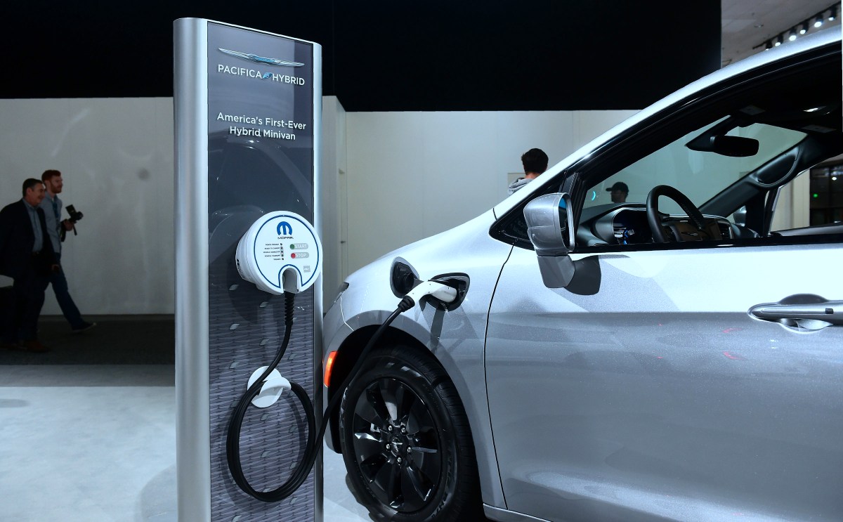 A white Chrysler Pacifica minivan at a charging station. 