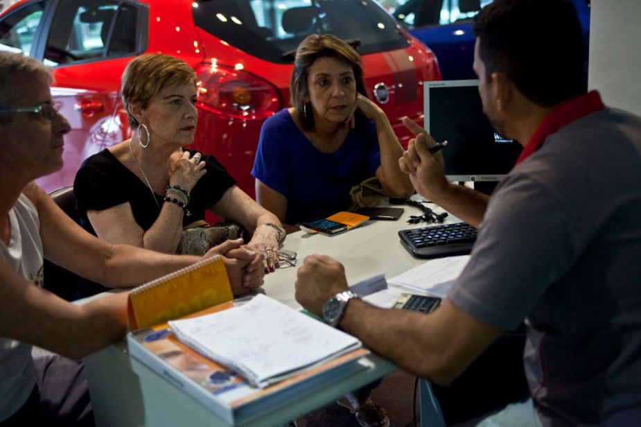 A salesperson explains payment options to shoppers at the Fiat SpA Eurobarra dealership in Rio de Janeiro, Brazil