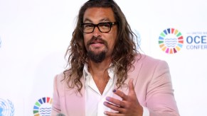 Jason Momoa, whom recently had a collision with a motorcyclist, wearing a pink suit and white button-up shirt.