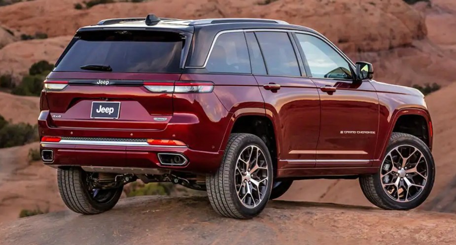 A red 2023 Jeep Grand Cherokee midsize SUV is parked off-road. 