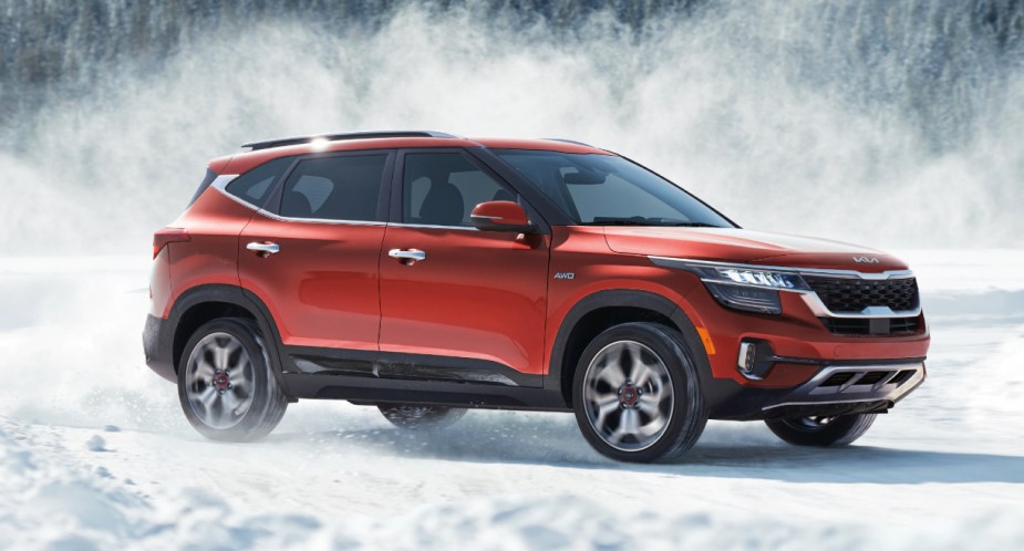 A red 2023 Kia Seltos subcompact SUV is parked with the snow. 