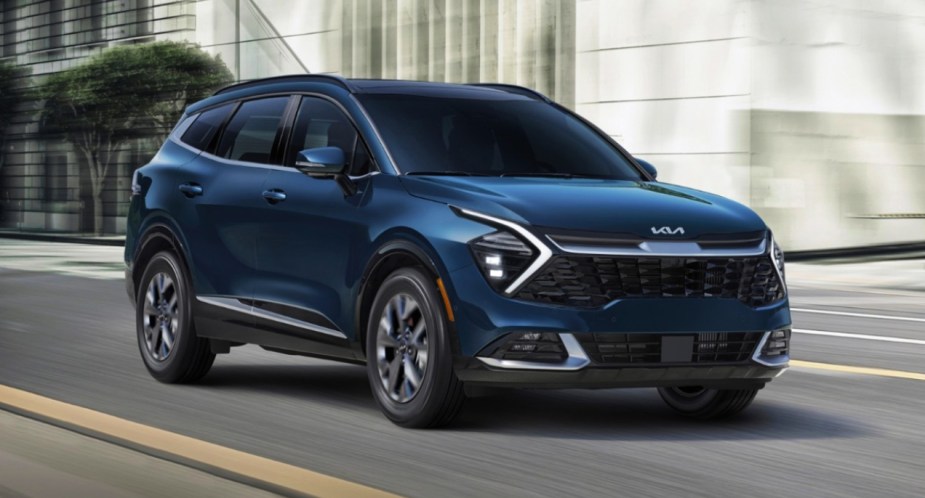 A blue Kia Sportage small SUV is driving on the road.