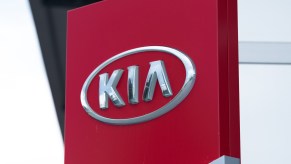 A red Kia sign with the logo. Some of the cars at the dealer could qualify for a free engine replacement.
