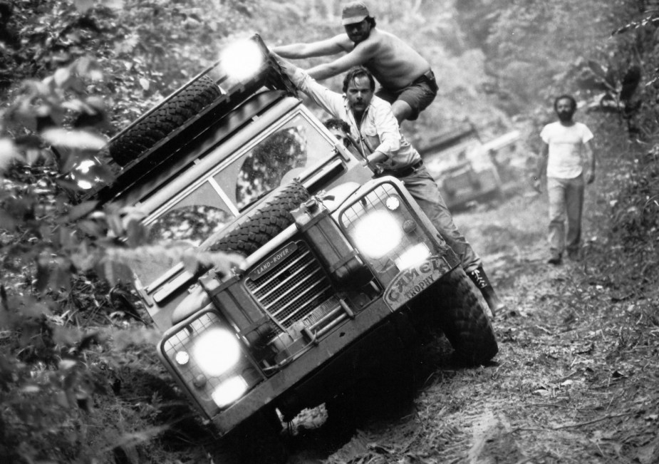 Black and white photo of the Camel Trophy team navigating an off-road trail with a basket roof rack.