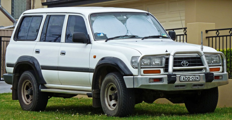An 80 series Toyota Land Cruiser in white sits parked in a yard.