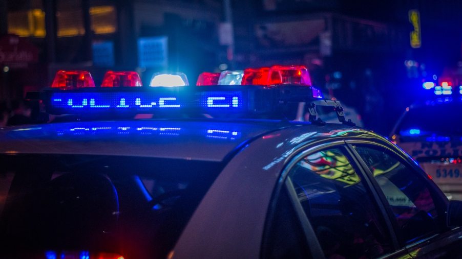 The roof of a police car with its red and blue emergency light bar flashing.